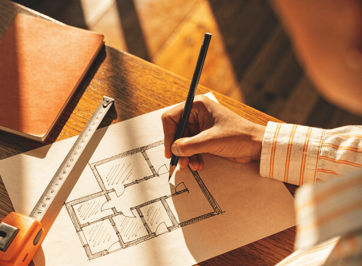 Illustration d'un devis en cours de préparation, main annotant un plan de logement